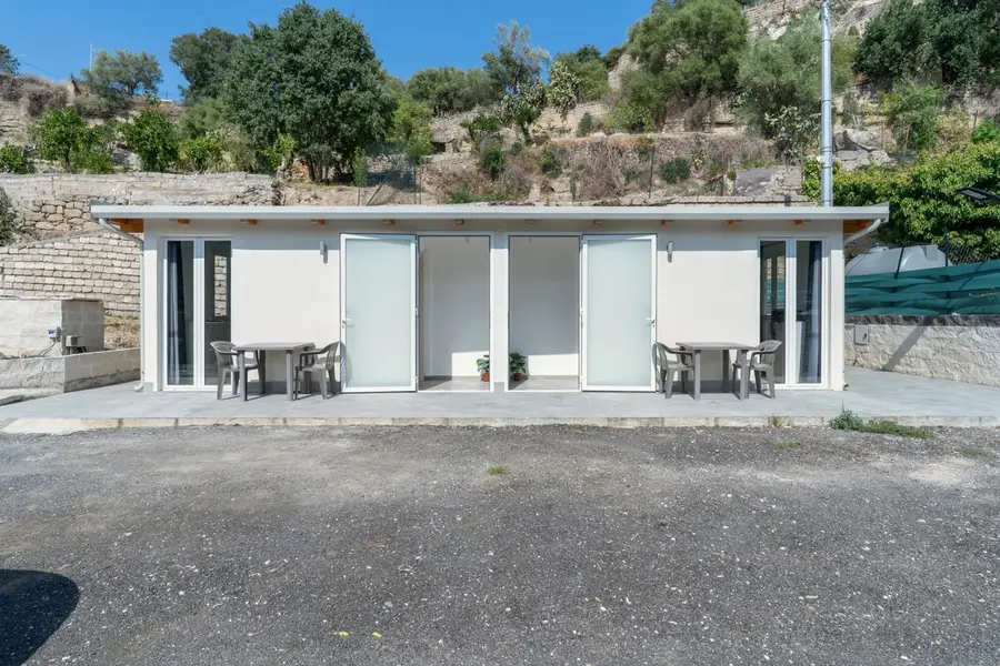 Facciata dei bungalow con le porte d'ingresso e i tavoli all'aperto