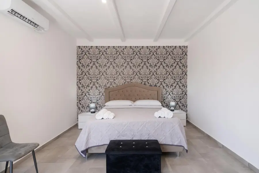 Stanza 1: letto matrimoniale davanti alla parete damascata