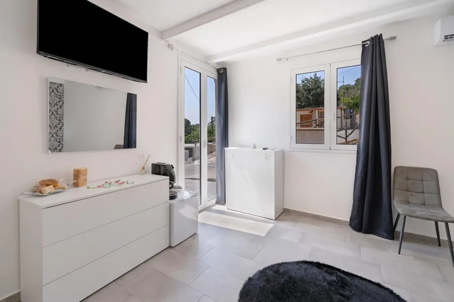Cassettiera, TV e specchio, con la porta-finestra aperta